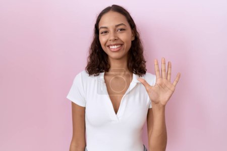 Photo for Young hispanic woman wearing casual white t shirt showing and pointing up with fingers number five while smiling confident and happy. - Royalty Free Image