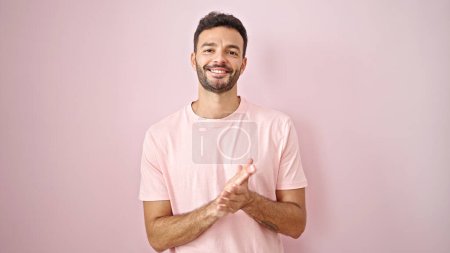 Téléchargez les photos : Jeune homme hispanique souriant mains claquement confiantes sur fond rose isolé - en image libre de droit