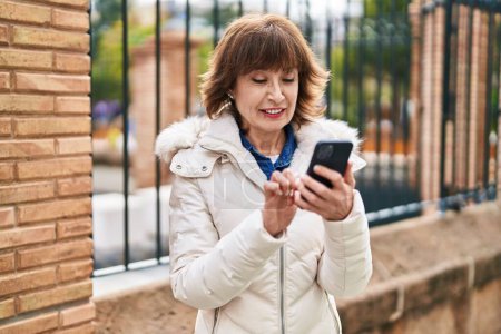 Photo for Middle age woman smiling confident using smartphone at street - Royalty Free Image