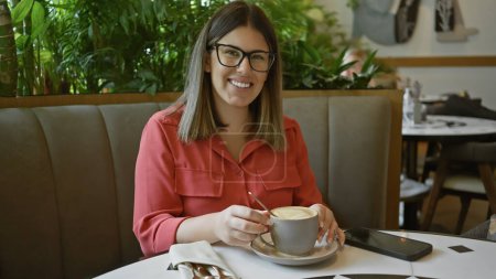 Photo for A smiling woman enjoys coffee in a cafe, showcasing a relaxed, casual dining experience. - Royalty Free Image