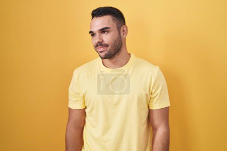 Téléchargez les photos : Young hispanic man standing over yellow background smiling looking to the side and staring away thinking. - en image libre de droit