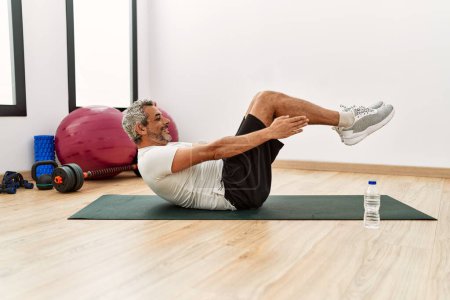 Photo for Middle age grey-haired man smiling confident training abs exercise at sport center - Royalty Free Image