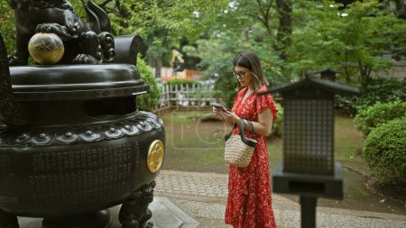 Foto de Mujer hispana en gafas captura la antigua belleza del templo Gotokuji de Japón con su teléfono, disfrutando de su papel como turista - Imagen libre de derechos