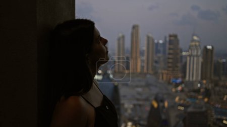 Téléchargez les photos : Une jeune femme adulte contemplative jouit de l'horizon dubai depuis un observatoire au crépuscule. - en image libre de droit