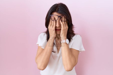 Photo for Middle age hispanic woman wearing casual white t shirt and glasses rubbing eyes for fatigue and headache, sleepy and tired expression. vision problem - Royalty Free Image