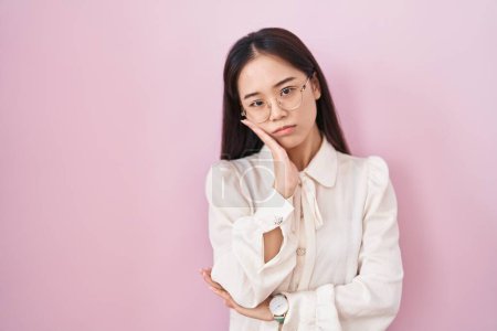 Téléchargez les photos : Jeune femme chinoise debout sur fond rose pensant fatigué et ennuyé avec des problèmes de dépression avec les bras croisés. - en image libre de droit