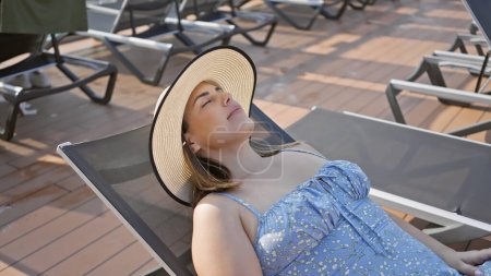 Téléchargez les photos : Une jeune femme se relaxant sur un pont de navire portant un chapeau de soleil, affichant loisirs, Voyage, et la tranquillité en mer. - en image libre de droit