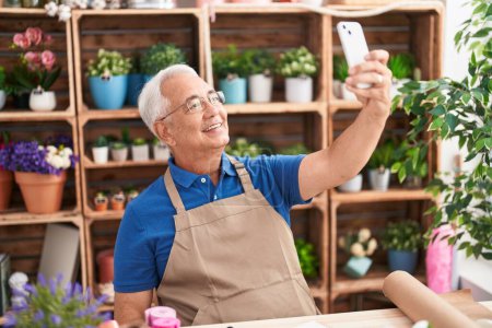 Photo for Middle age grey-haired man florist make selfie by smartphone at florist - Royalty Free Image
