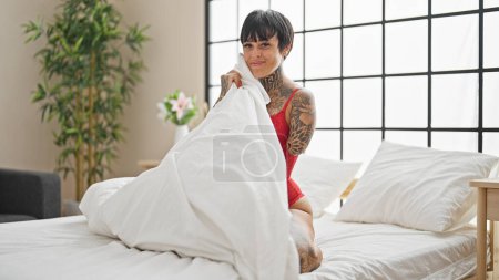 Téléchargez les photos : Femme hispanique avec bras amputé portant de la lingerie assis sur le lit couvrant avec couverture dans la chambre - en image libre de droit