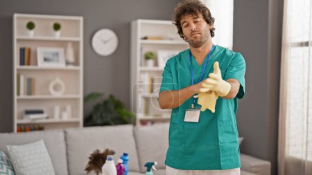 Photo for Young hispanic man professional cleaner wearing gloves smiling at home - Royalty Free Image