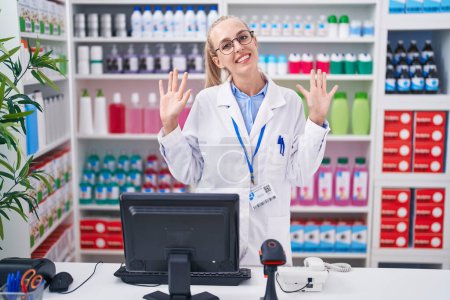 Photo for Young caucasian woman working at pharmacy drugstore showing and pointing up with fingers number ten while smiling confident and happy. - Royalty Free Image