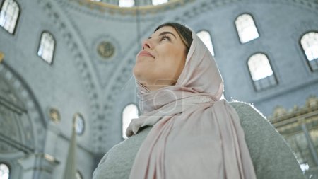 Téléchargez les photos : Une femme contemplative portant un hijab dans une mosquée historique istanbul regarde vers le haut. - en image libre de droit