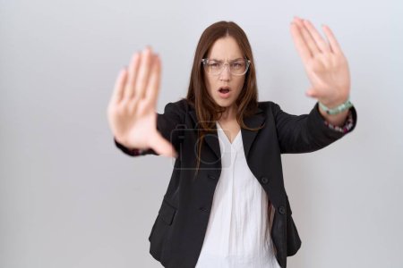 Photo for Beautiful brunette woman wearing business jacket and glasses doing stop gesture with hands palms, angry and frustration expression - Royalty Free Image