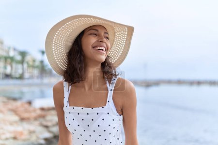Foto de Young african american woman wearing summer hat looking to the side at seaside - Imagen libre de derechos