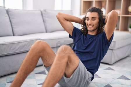 Photo for Young hispanic man smiling confident training abs exercise at home - Royalty Free Image