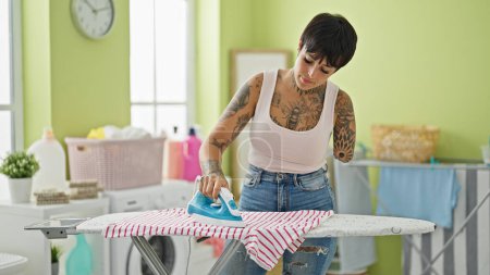 Hispanic woman with amputee arm ironing clothes at laundry room