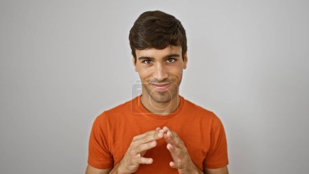 Photo for Attractive, cheerful young hispanic guy flashing a confident smile while standing, fingers interlocked, isolated on a white background - capturing the joy of a casual lifestyle. - Royalty Free Image