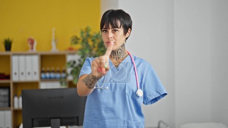 Téléchargez les photos : Femme hispanique avec amputé bras médecin debout avec une expression sérieuse disant non avec un doigt à la clinique - en image libre de droit
