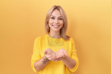 Photo for Young caucasian woman wearing yellow sweater smiling with hands palms together receiving or giving gesture. hold and protection - Royalty Free Image