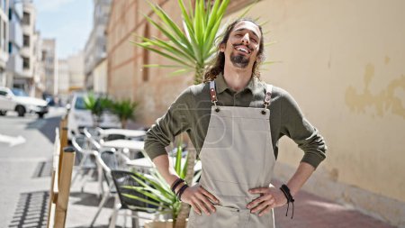 Photo for Young hispanic man waiter smiling confident standing at coffee shop terrace - Royalty Free Image