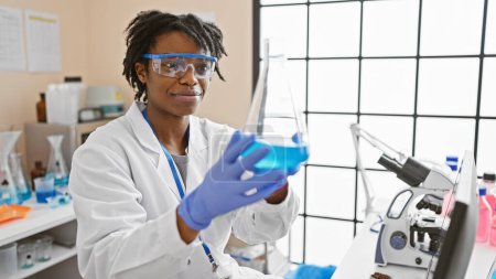 Photo for African woman scientist examining a flask in modern laboratory setting - Royalty Free Image