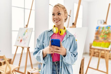 Photo for Young caucasian woman artist using smartphone standing at art studio - Royalty Free Image