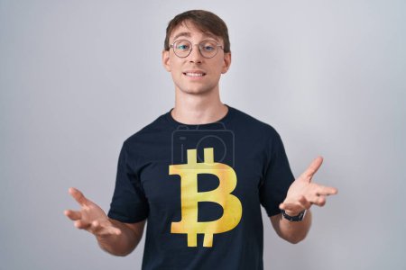 Photo for Caucasian blond man wearing bitcoin t shirt smiling cheerful offering hands giving assistance and acceptance. - Royalty Free Image