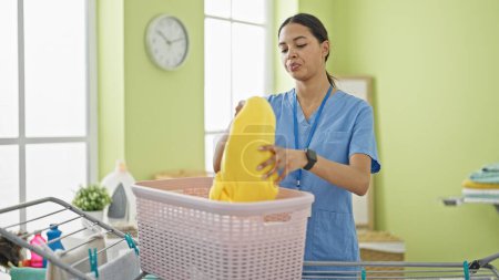 Foto de Mujer afroamericana limpiadora profesional colgando ropa en tendedero en la sala de lavandería - Imagen libre de derechos