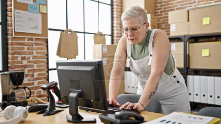 Foto de La mujer de pelo gris de mediana edad comercio electrónico trabajador de negocios utilizando la computadora que trabaja en la oficina - Imagen libre de derechos