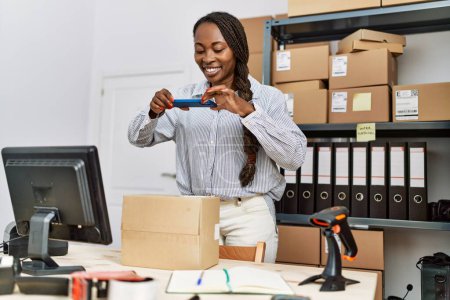 Foto de African american woman ecommerce business worker make photo to package at office - Imagen libre de derechos