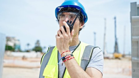 Téléchargez les photos : Jeune architecte hispanique parlant sur talkie-walkie sur le lieu de construction - en image libre de droit