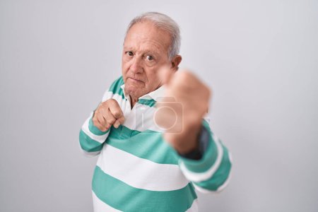 Photo for Senior man with grey hair standing over white background punching fist to fight, aggressive and angry attack, threat and violence - Royalty Free Image