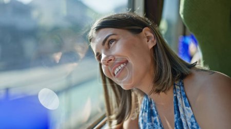 Photo for Cheerful, beautiful hispanic woman enjoying her railway journey, smiling while looking through the train window - Royalty Free Image