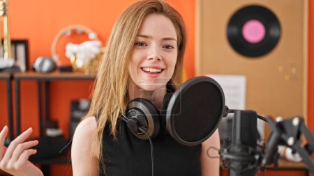 Photo for Young blonde woman musician smiling confident singing song at music studio - Royalty Free Image