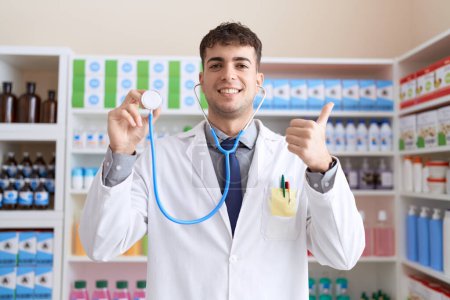Photo for Young hispanic man wearing doctor uniform and stethoscope pointing thumb up to the side smiling happy with open mouth - Royalty Free Image