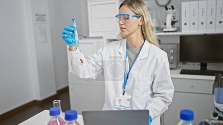 Photo for A professional woman scientist examines a test tube in a modern laboratory setting. - Royalty Free Image