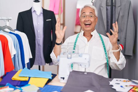 Photo for Middle age man with grey hair dressmaker using sewing machine celebrating crazy and amazed for success with arms raised and open eyes screaming excited. winner concept - Royalty Free Image