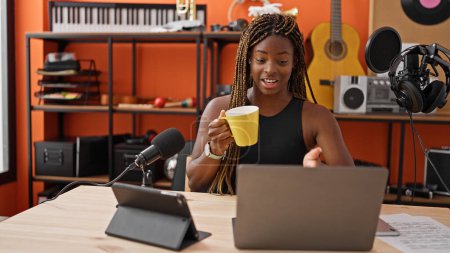 Téléchargez les photos : Journaliste afro-américaine ayant émission de radio boire une tasse de café au studio de musique - en image libre de droit