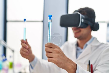 Photo for Young hispanic man scientist using virtual reality glasses holding test tubes at laboratory - Royalty Free Image