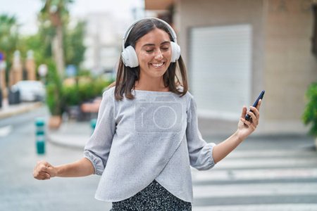 Téléchargez les photos : Jeune belle femme hispanique écoutant de la musique et dansant dans la rue - en image libre de droit