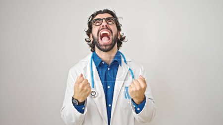 Foto de Joven médico hispano enojado y estresado sobre fondo blanco aislado - Imagen libre de derechos