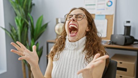 Foto de Mujer joven riendo alegremente en una oficina moderna, retratando positividad y felicidad en el trabajo. - Imagen libre de derechos