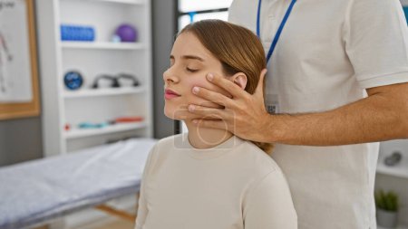 Photo for Male therapist gently examining female patient's neck in a well-equipped physiotherapy clinic. - Royalty Free Image