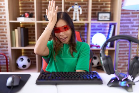 Photo for Middle age chinese woman wearing virtual reality glasses surprised with hand on head for mistake, remember error. forgot, bad memory concept. - Royalty Free Image