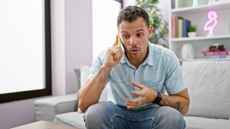 Photo for Handsome young man with beard talking on phone in modern cozy apartment living room. - Royalty Free Image