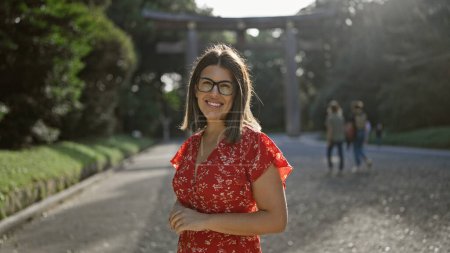 Photo for Cheerful, beautiful hispanic woman with glasses poses confidently, smiling at tokyo's meiji shrine, her joy unequivocally radiating through her astonishing smile - Royalty Free Image