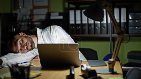 Photo for Young hispanic man business man leaning on table sleeping at the office - Royalty Free Image