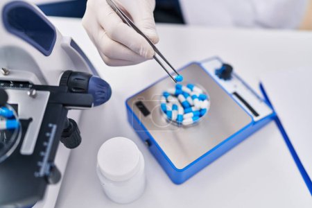 Téléchargez les photos : Jeune homme scientifique pesant des pilules au laboratoire - en image libre de droit
