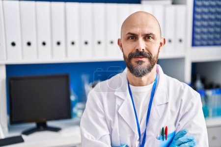 Photo for Young bald man scientist smiling confident sitting with arms crossed gesture at laboratory - Royalty Free Image