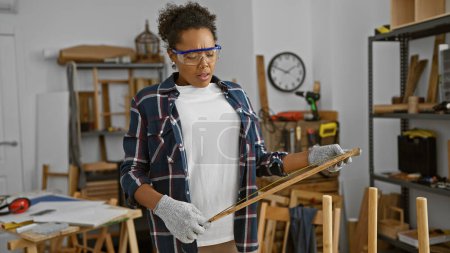 Photo for A focused woman measures wood in a well-equipped carpentry workshop - Royalty Free Image